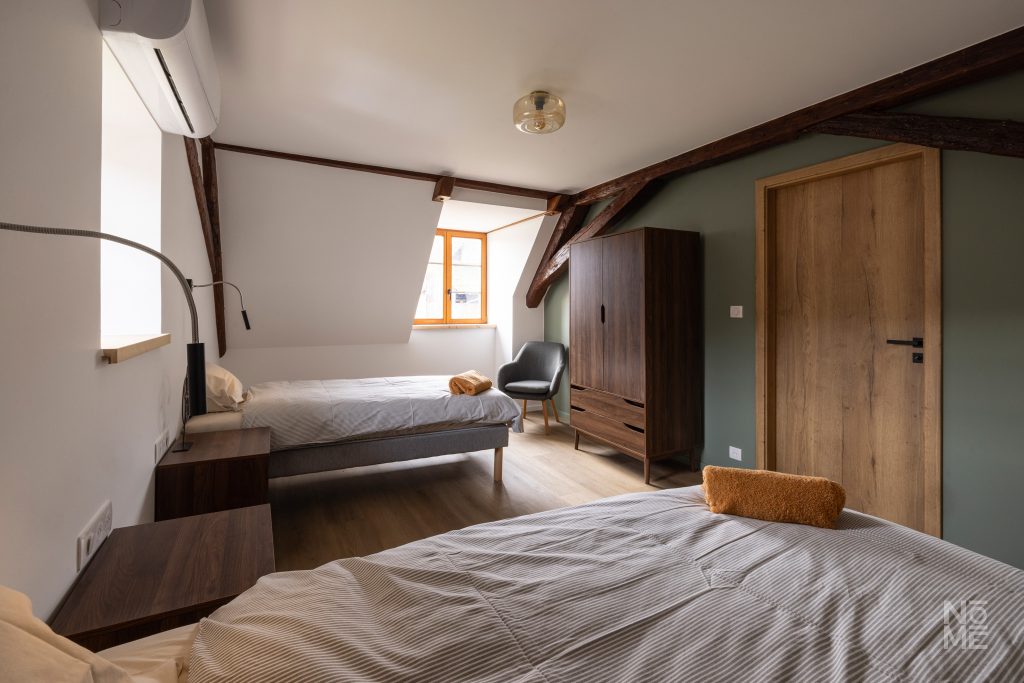 Chambre avec poutres apparentes du gîte des 4 Fontaines rénovée par Atelier NŌMĒ